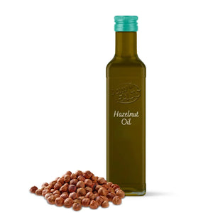 Bottle of hazelnut oil with a pile of hazelnuts on a white background